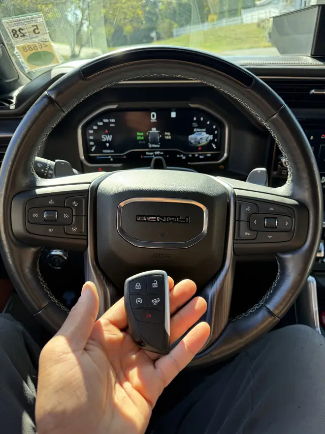 GMC smart key held in front of a GMC Denali steering wheel