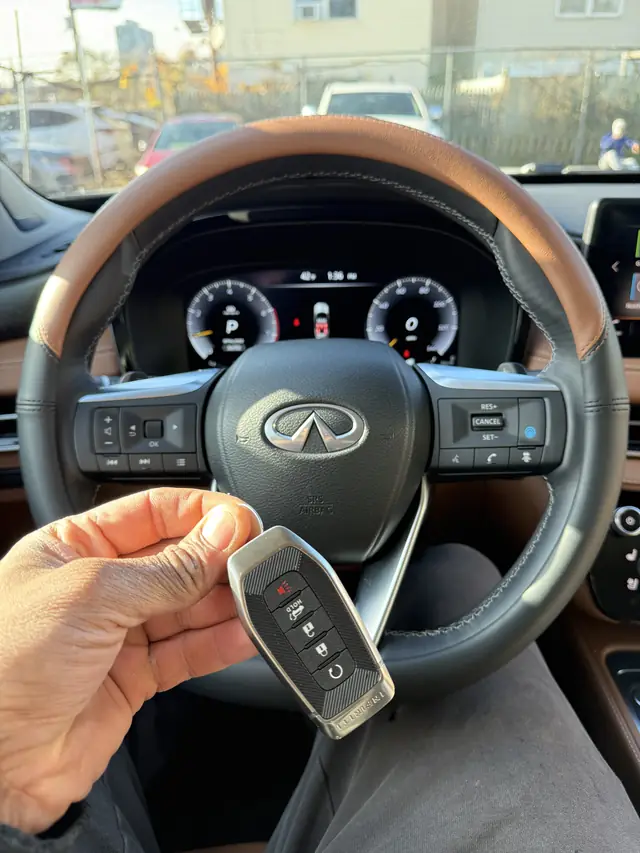 Infiniti smart key held in front of an Infiniti steering wheel