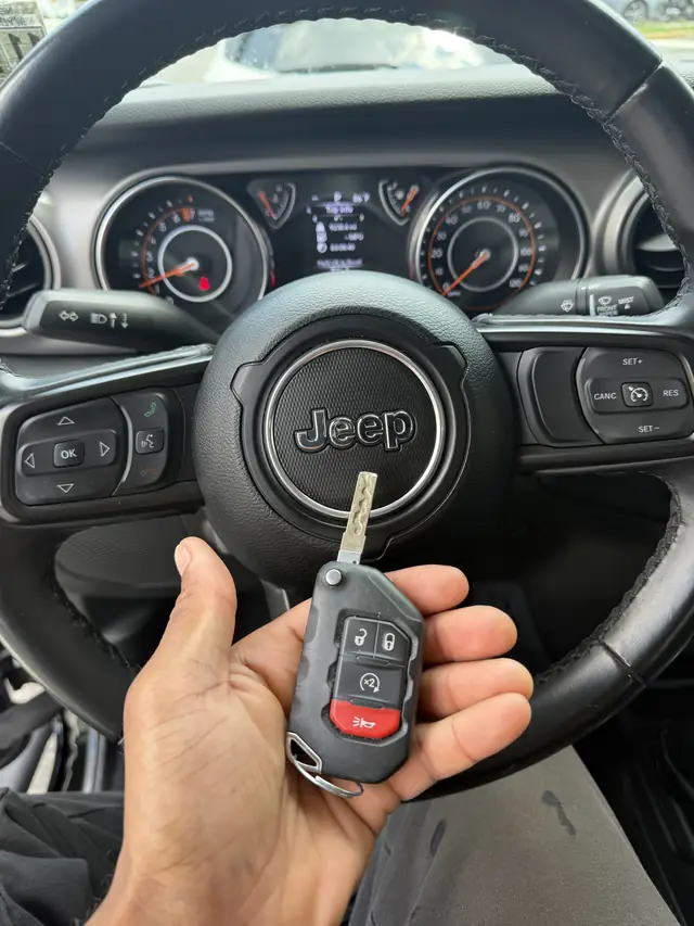 Jeep flip key held in front of a Jeep steering wheel