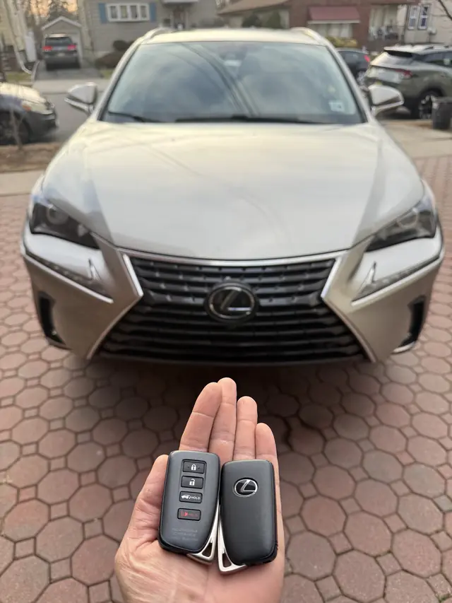 Two Lexus smart keys held in front of a Lexus SUV
