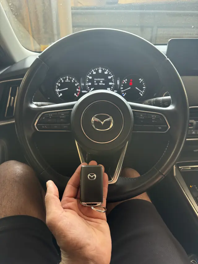 Mazda smart key held in front of a Mazda steering wheel