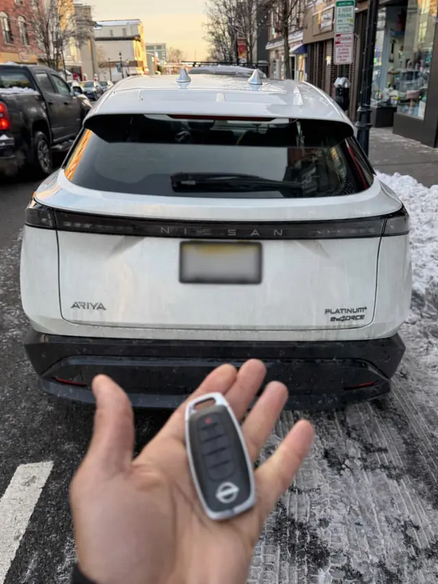 Nissan smart key held in front of a white Nissan SUV
