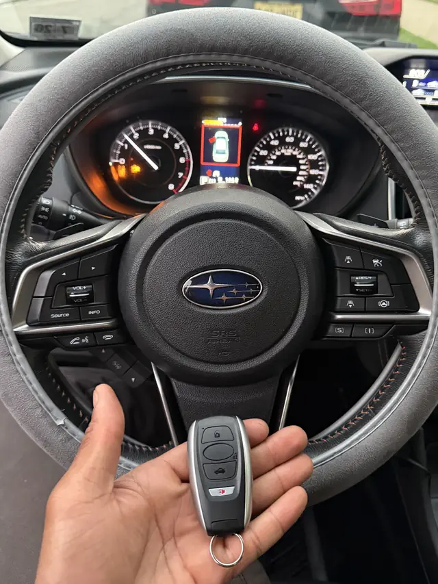 Subaru smart key held in front of a Subaru steering wheel